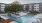a pool with chairs and umbrellas by a building